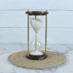 A classic handmade 3-minute sand timer with white sand, framed by dark wooden bases and shiny brass pillars.