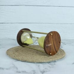 Angled view of the 3-minute hourglass, showing the rich grain of the round wooden base and brass hardware.