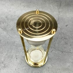 A top-down view of the 5-minute hourglass, showing the engraved concentric circles on its shiny brass plate.