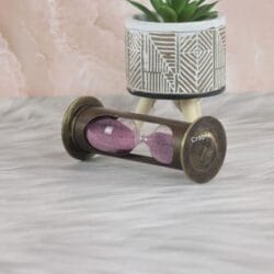 The antique brass 1-minute hourglass used as a decorative desktop accessory with a plant.