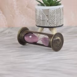 The antique brass 1-minute hourglass used as a decorative desktop accessory with a plant.