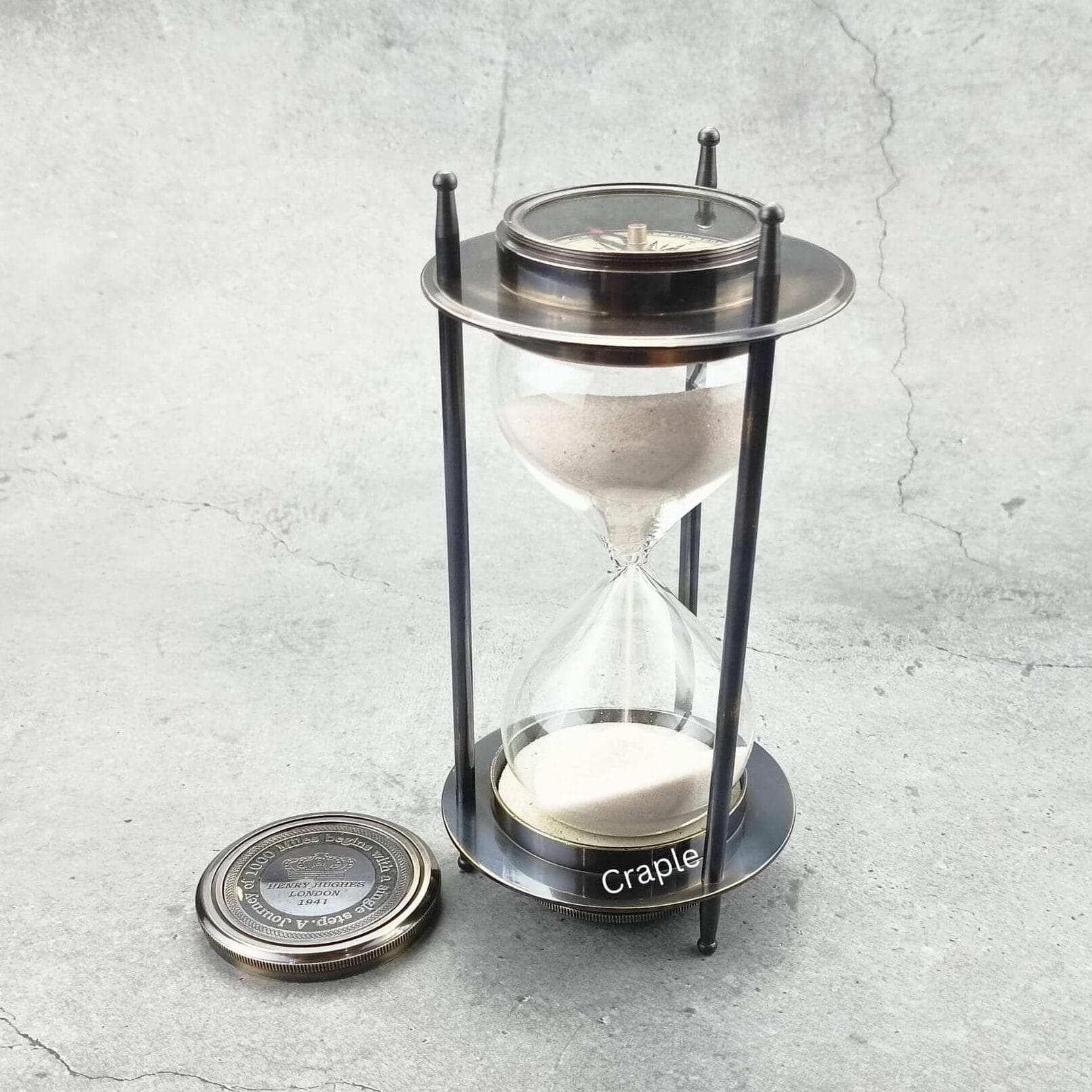 Dual Compass 5-Minute Sand Timer-4 A vintage 5-minute hourglass with a black antique brass frame, white sand flowing, and a detachable compass.