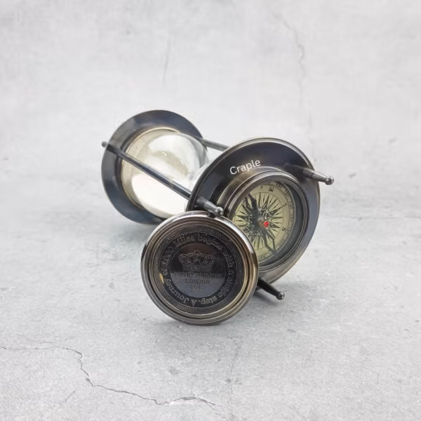 The hourglass sand timer lying on its side with one compass on top and a second detached compass visible.