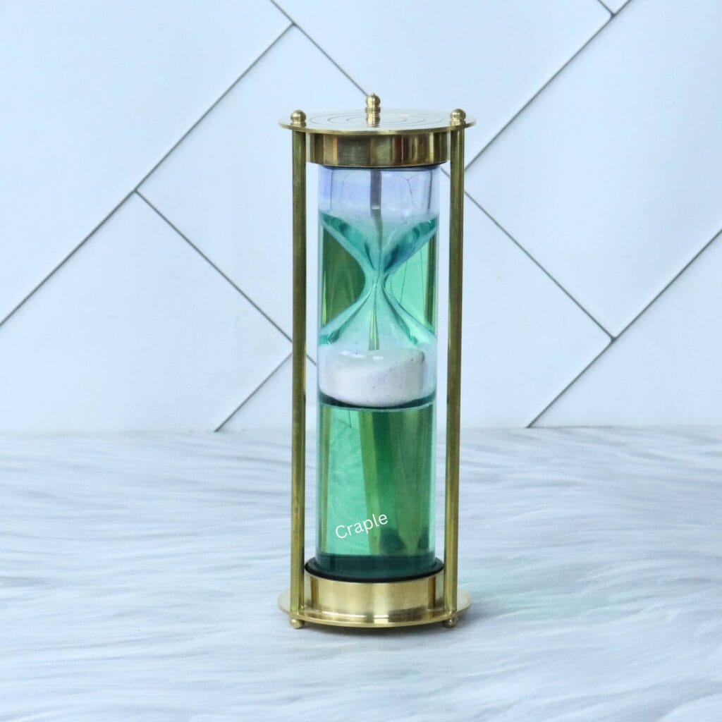 A unique 1-minute floating sand timer with white sand falling through a green liquid, housed in a shiny brass frame.