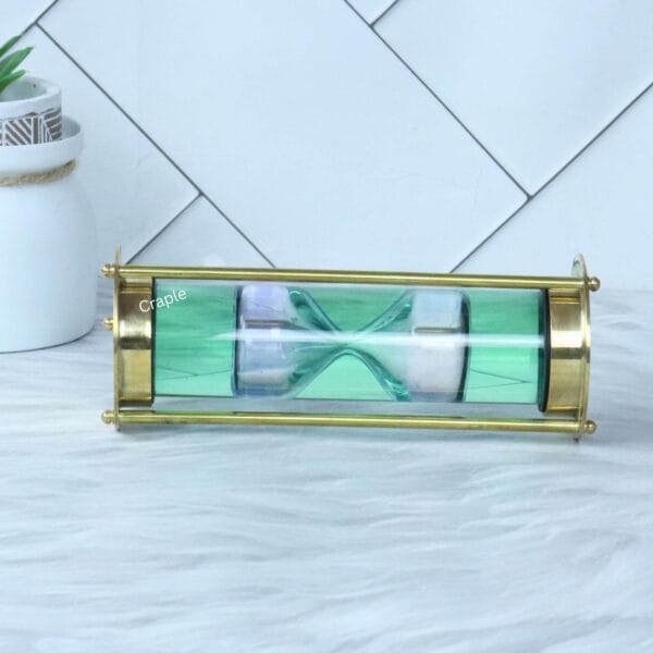 The 1-minute white sand liquid timer viewed horizontally, showcasing its sleek cylindrical design and brass pillars.