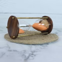The 5-minute orange sand hourglass lying on its side, showcasing its sturdy construction and elegant design.