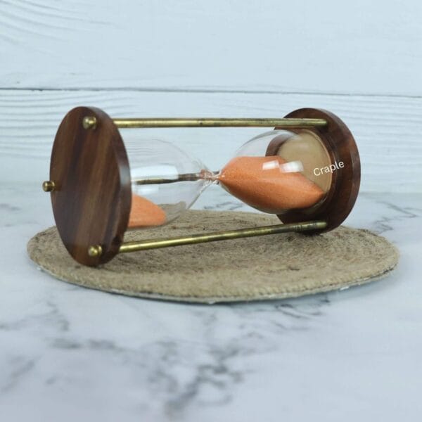 The 5-minute orange sand hourglass lying on its side, showcasing its sturdy construction and elegant design.