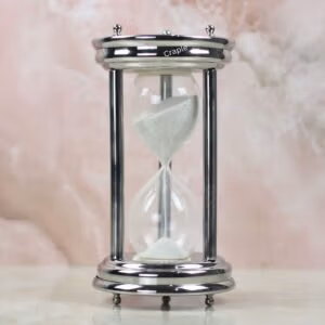 A handcrafted 10-minute hourglass with a polished steel frame, sturdy pillars, and fine white sand.
