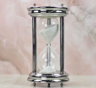 A handcrafted 10-minute hourglass with a polished steel frame, sturdy pillars, and fine white sand.