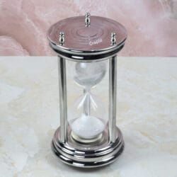 High-angle view of the steel sand timer, detailing the engraved circular pattern on the top plate.