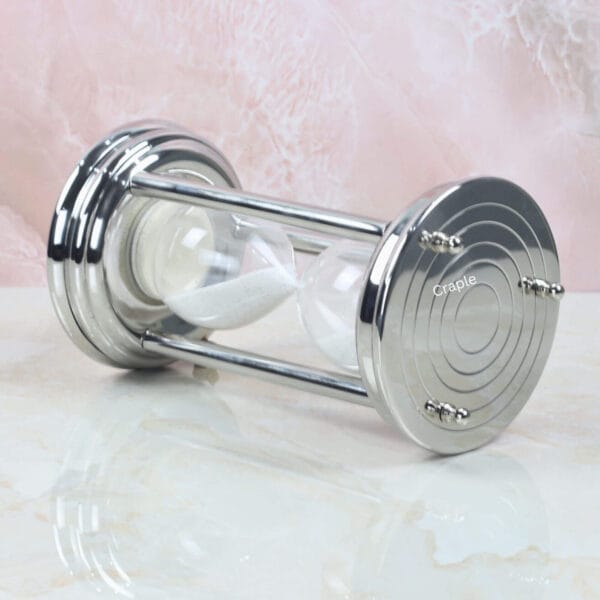 Angled side view of the modern steel sand timer, highlighting its reflective, polished finish.