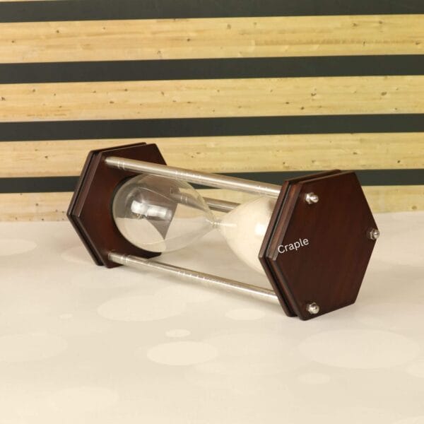 The hexagonal white sand timer resting horizontally on a surface, showcasing its nickel-finish pillars.