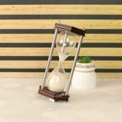 The hexagonal sand timer displayed as a stylish office accessory, leaning against a small plant.