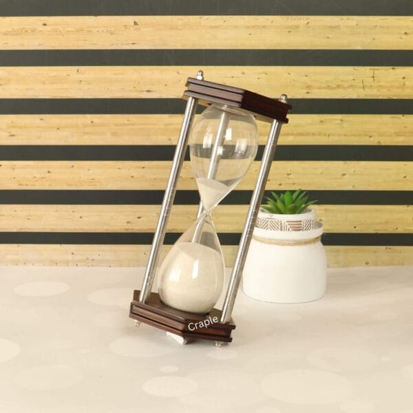 The hexagonal sand timer displayed as a stylish office accessory, leaning against a small plant.
