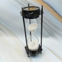 Angled profile of the antique-finish brass hourglass, highlighting its hexagonal base and support pillars.