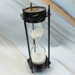 A three-quarter view of the dual compass sand timer, showing both the hourglass and the compass top.
