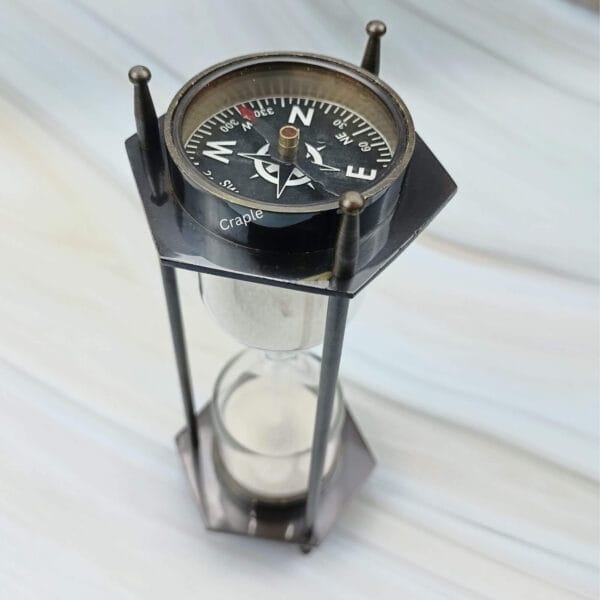 Angled view focusing on the vintage-style compass at the top of the 3-minute sand timer.