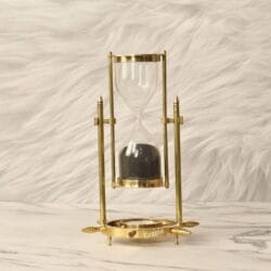 A vintage-style rotating brass sand timer with black sand, featuring a "Kelvin & Hughes London" engraved top.