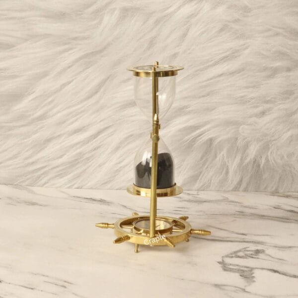 The base of the brass hourglass, designed as a ship's wheel with an integrated magnetic compass in the center.