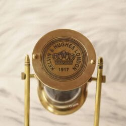 Close-up of the polished brass top of the sand timer, showing the "Kelvin & Hughes London 1917" engraving.