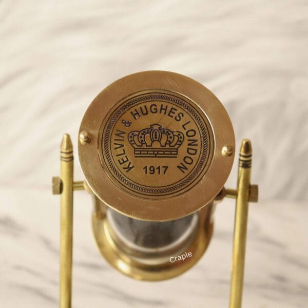 Close-up of the polished brass top of the sand timer, showing the "Kelvin & Hughes London 1917" engraving.