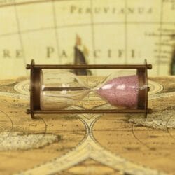 Side profile of the 1-minute brass and glass sand timer, lying horizontally on a vintage map.