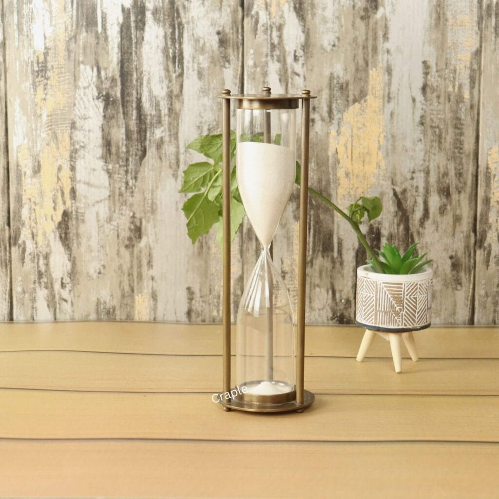 An elegant, tall, and slim 15-minute hourglass with white sand, framed by antique-finish brass pillars.