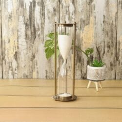 An elegant, tall, and slim 15-minute hourglass with white sand, framed by antique-finish brass pillars.