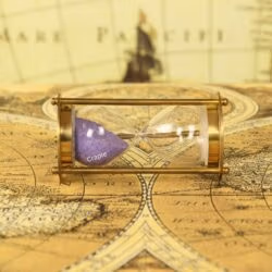 The small brass and purple sand hourglass resting horizontally on a vintage world map.