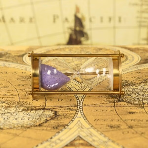 The small brass and purple sand hourglass resting horizontally on a vintage world map.
