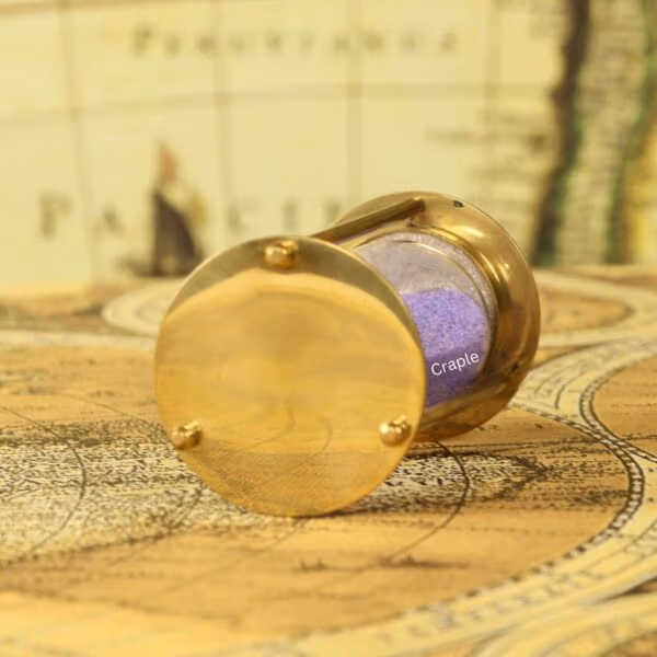 Close-up of the polished, shiny brass base of the petite 1-minute sand timer.
