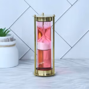 An elegant pink liquid floating hourglass with a shiny brass frame, showing the internal sand timer.
