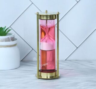 An elegant pink liquid floating hourglass with a shiny brass frame, showing the internal sand timer.
