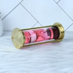 End view of the floating hourglass, showing the polished brass end cap and the pink liquid-filled glass tube.