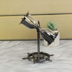 The nautical sand timer swiveling within its black antique brass frame, with black sand flowing through the glass.