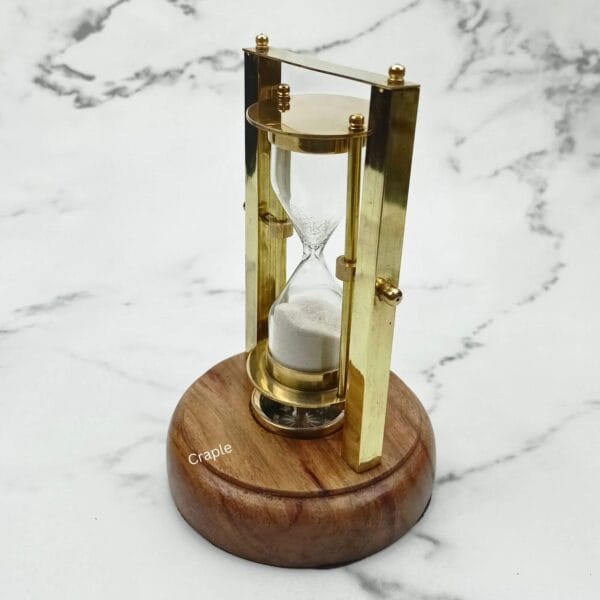 Angled side view of a rotating hourglass with a brass and wood frame on a circular wooden base.