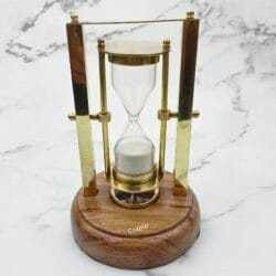Front view of the desktop sand timer, showing the white sand and the brass frame on a wood base.