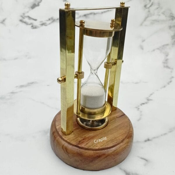 Three-quarter view of the executive brass hourglass with an integrated compass in the base.
