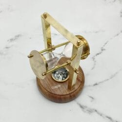 The brass hourglass tilted back in its swivel, revealing the working compass in the wooden base.