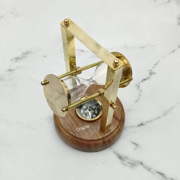 The brass hourglass tilted back in its swivel, revealing the working compass in the wooden base.