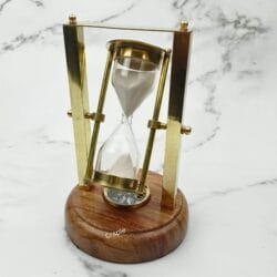 Elegant rotating hourglass sand timer with a shiny brass and wood frame on a round wooden base with a built-in compass.