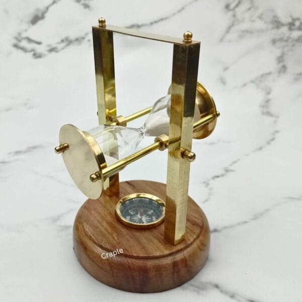 The white sand hourglass tilted sideways within its polished brass pivoting frame.