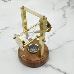 The hourglass fully tilted back, providing a clear view of the decorative compass in the wood base.