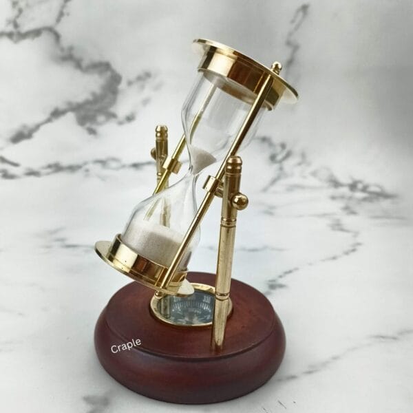 The rotating brass hourglass and compass viewed from an angle, highlighting its reflective shiny brass finish.