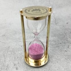 Angled view of the Royal Navy sand timer, highlighting its solid brass construction and glass bulb.