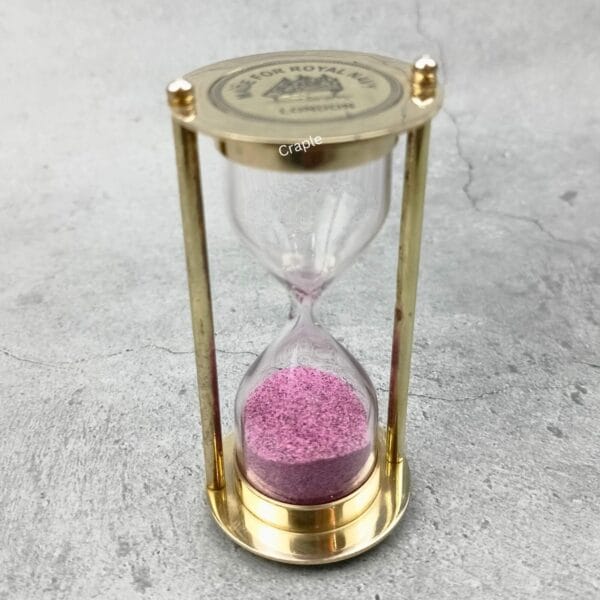 Angled view of the Royal Navy sand timer, highlighting its solid brass construction and glass bulb.