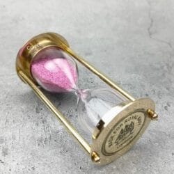 The brass and pink sand hourglass tilted on its side, showing the "Royal Navy" engraving.