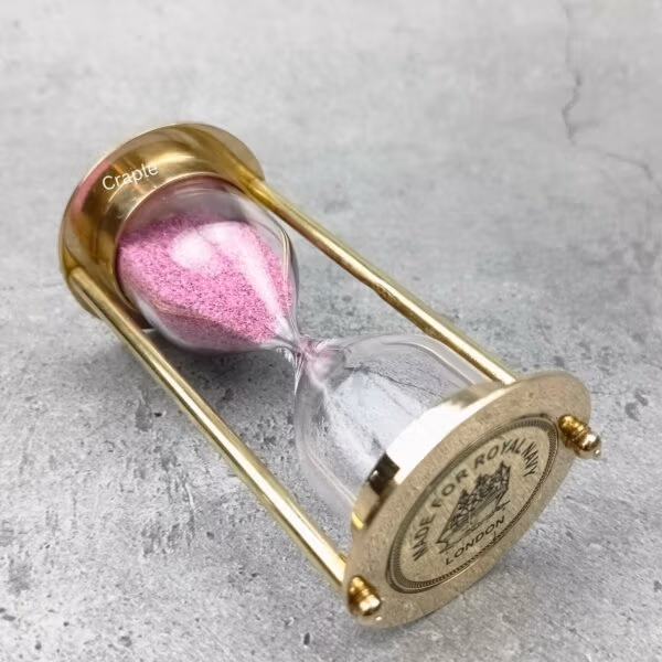 The brass and pink sand hourglass tilted on its side, showing the "Royal Navy" engraving.