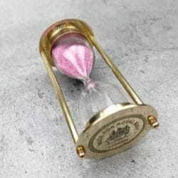 The pink sand and brass 3-minute timer shown from an angled side profile.