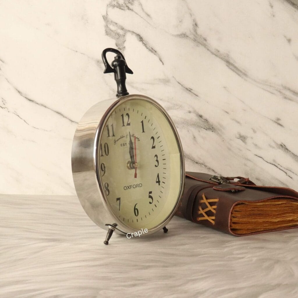 Angled view of the silver desk and hanging clock, highlighting its polished aluminum casing and sturdy construction.